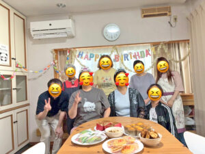 「HAPPY BIRTHDAY」のガーランドを背景に、参加者全員が笑顔で並んでいる集合写真。テーブルには作ったお菓子が並んでいる。